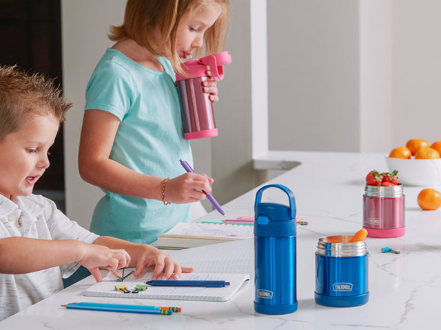 Kids standing a kitchen counter with their Thermos water bottles and food jars.