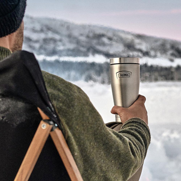 Man holding Thermos 16oz tumbler in front of a snowy mountain.