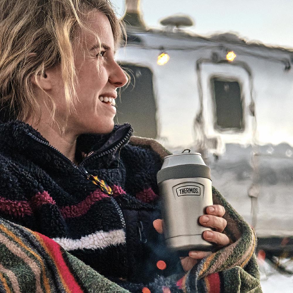 Woman holding a can in a Thermos can insulator.